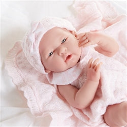 Newborn baby in a pink outfit with a bonnet on a light background