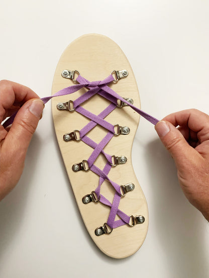 Person tying purple laces on a wooden shoe dexterity and hand eye coordination activity