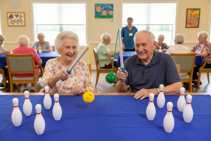 Group of seniors playing a game of bowling at a table in a care home setting.